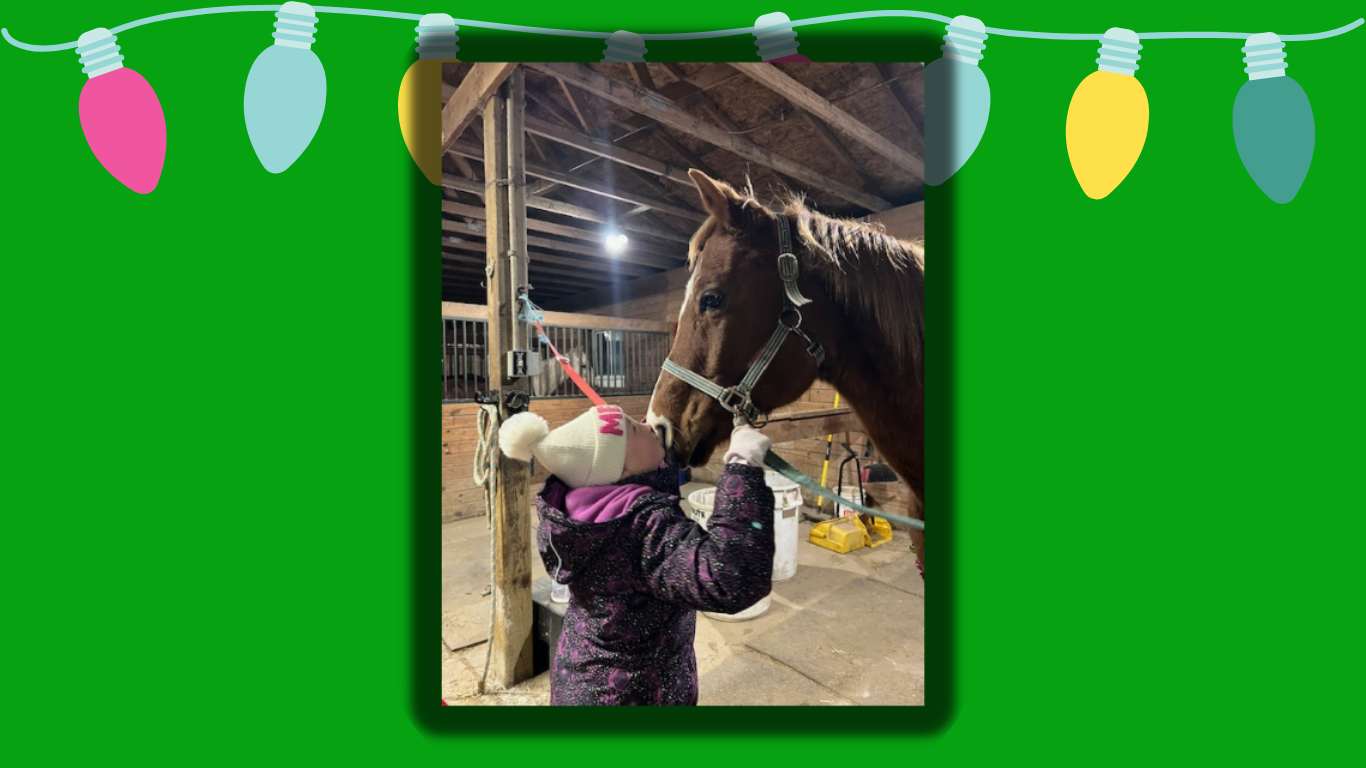 Girl, about the same height as the horse's muzzle when the head is lifted, tilts her head upward to kiss the muzzle of a chestnut horse wearing a light green halter, in cross ties; girl on left, horse on right, both in profile.